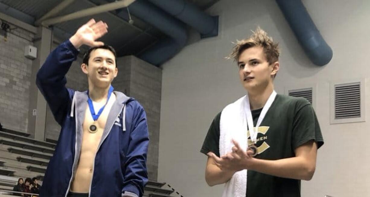 Evergreen's Ilia Zablotovskii (right) applauds as Jude Wenker of Bellevue is acknowledged for his meet record in the 100 freestyle.