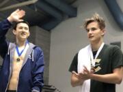 Evergreen's Ilia Zablotovskii (right) applauds as Jude Wenker of Bellevue is acknowledged for his meet record in the 100 freestyle.