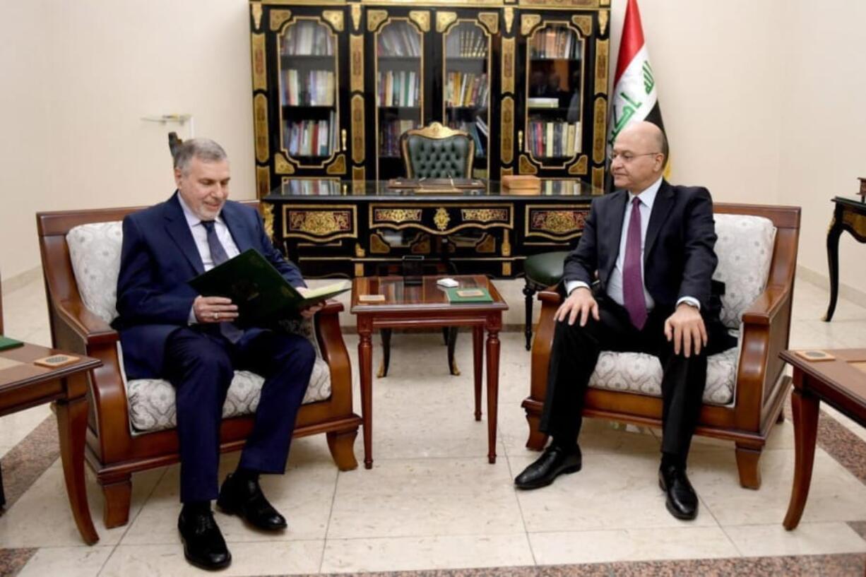 Iraqi President Barham Salih, right, instructs newly appointed Prime Minister Mohammed Allawi on Saturday in Baghdad, Iraq.