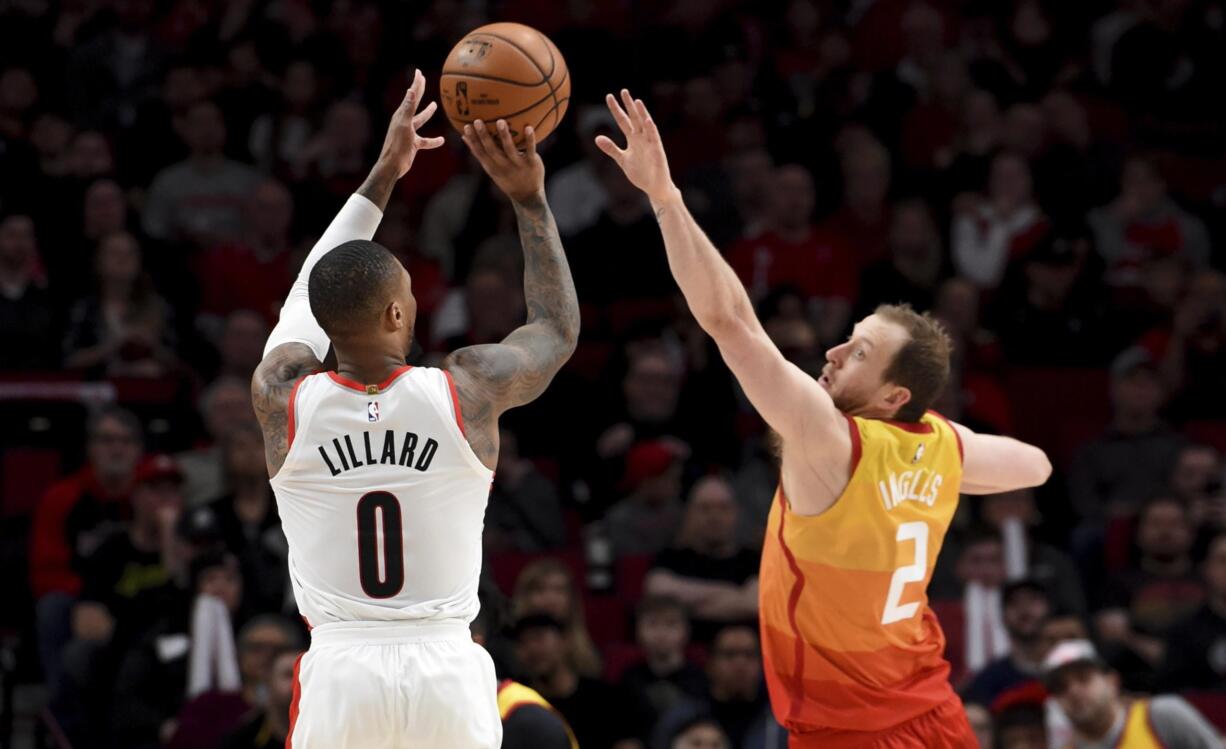 Portland Trail Blazers guard Damian Lillard, left, hits a shot over Utah Jazz guard Joe Ingles, right, during the second half of an NBA basketball game in Portland, Ore., Saturday, Feb. 1, 2020. The Blazers won 124-107.