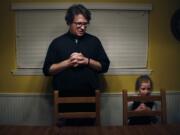 In this Feb. 7, 2020, photo, converted Catholic Priest Joshua Whitfield, left, his daughter Zoe-Catherine, 5, and the rest of his family stand behind their chairs to say grace before dinner in north Dallas.