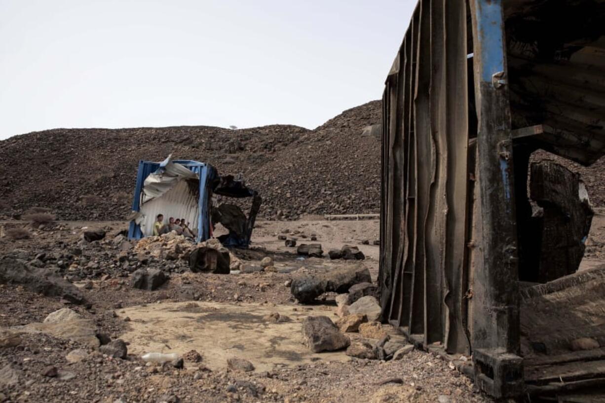 In this July 14, 2019 photo, 35-year-old Mohammed Eissa, an Ethiopian farmer and other migrants he met along the way, take shelter inside a damaged shipping container on the side of a highway, near Lac Assal, Djibouti. Over the past three years, the IOM reported 9,000 Ethiopians were deported each month. Many migrants have made the journey multiple times in what has become an unending loop of arrivals and deportations. Eissa is among them. This is his third trip to Saudi Arabia.