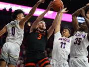 Oregon State forward Tres Tinkle (3) drives between Arizona guard Josh Green (0), Ira Lee (11), and Christian Koloko (35) during the first half of an NCAA college basketball game Thursday, Feb. 20, 2020, in Tucson, Ariz.