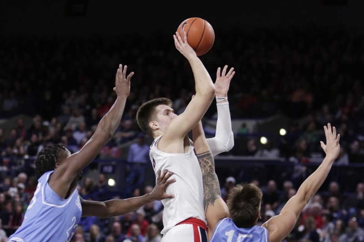 Gonzaga forward Filip Petrusev, center, shoots between San Diego forward James Jean-Marie, left, and forward Alex Floresca during the first half of an NCAA college basketball game in Spokane, Wash., Thursday, Feb. 27, 2020.