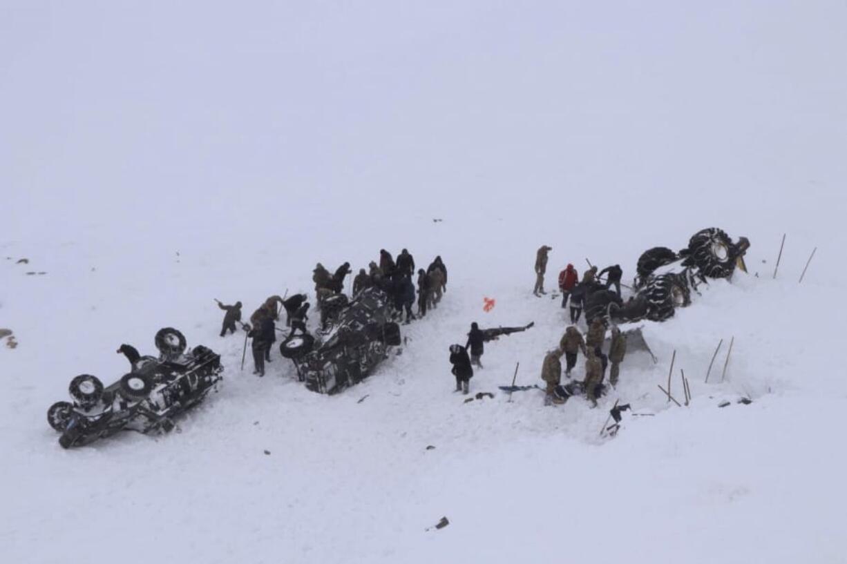 Emergency service members dig in the snow around at least three overturned vehicles, near the town of Bahcesehir, in Van province, eastern Turkey, Wednesday, Feb. 5, 2020.