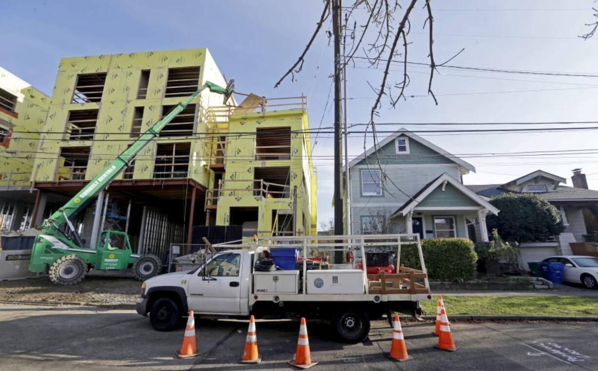 FILE - In this Dec. 13, 2017 file photo, a four-story mixed-use building is under construction adjacent to an older, single-family home in Seattle. A massive influx of new residents and an ensuing housing crunch has led to skyrocketing rents. On Monday, Feb. 10, 2020, the Seattle City Council unanimously approved a ban on evictions during December, January and February.