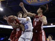 UCLA guard Tyger Campbell (10) vies for a rebound against Washington State guard Jervae Robinson (1) and forward DJ Rodman (11) during the first half of an NCAA college basketball game Thursday, Feb. 13, 2020, in Los Angeles.