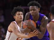 Southern California forward Max Agbonkpolo, left, ties up Washington guard Nahziah Carter during the first half of an NCAA college basketball game Thursday, Feb. 13, 2020, in Los Angeles. (AP Photo/Mark J.