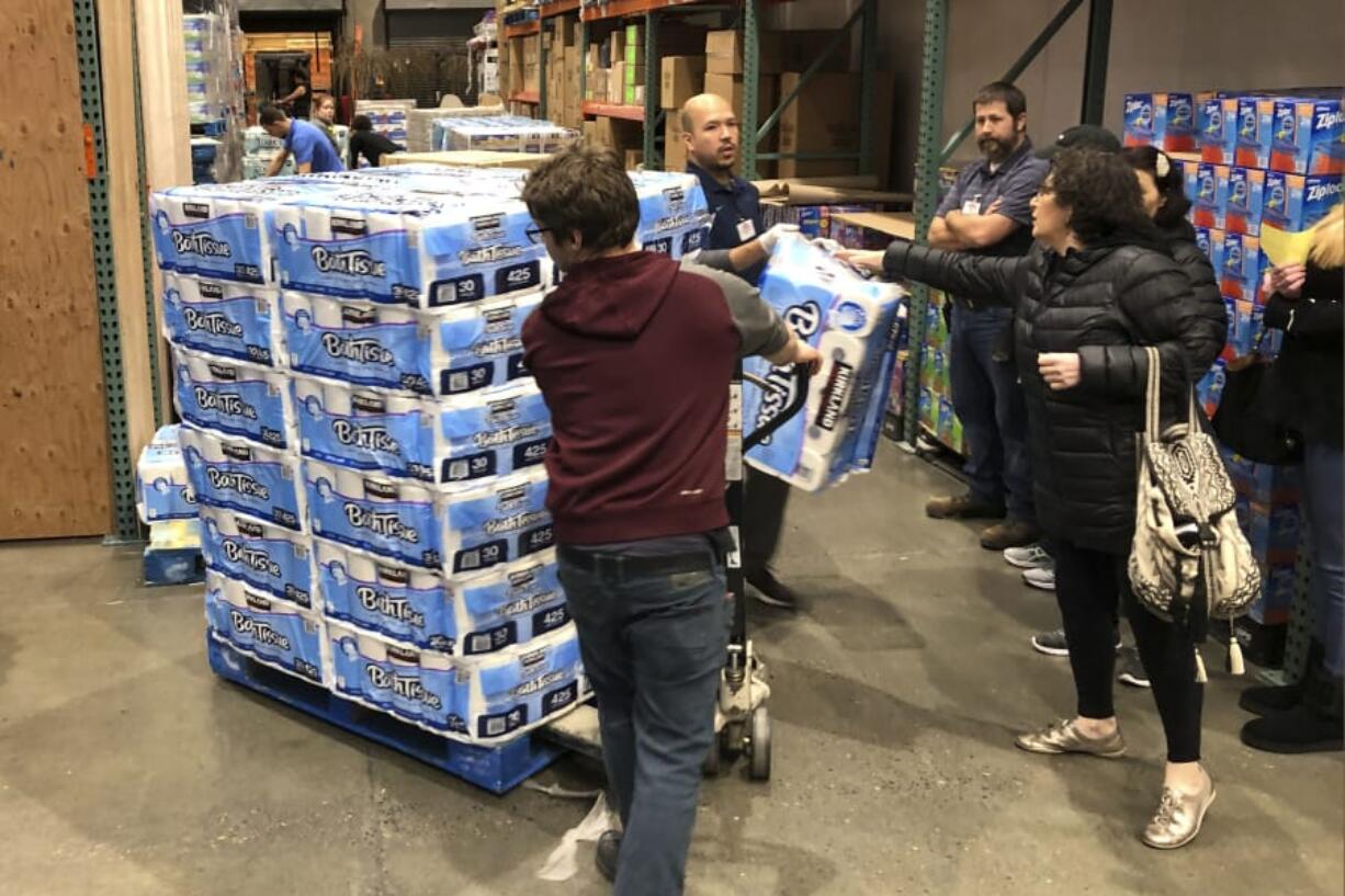 Shoppers rush to pick up toilet paper that had just arrived at a Costco store Saturday in Tacoma. Within minutes, several pallets of toilet paper and paper towels were sold out as people continue to stock up on necessities due to fear of the coronavirus. (ted s.