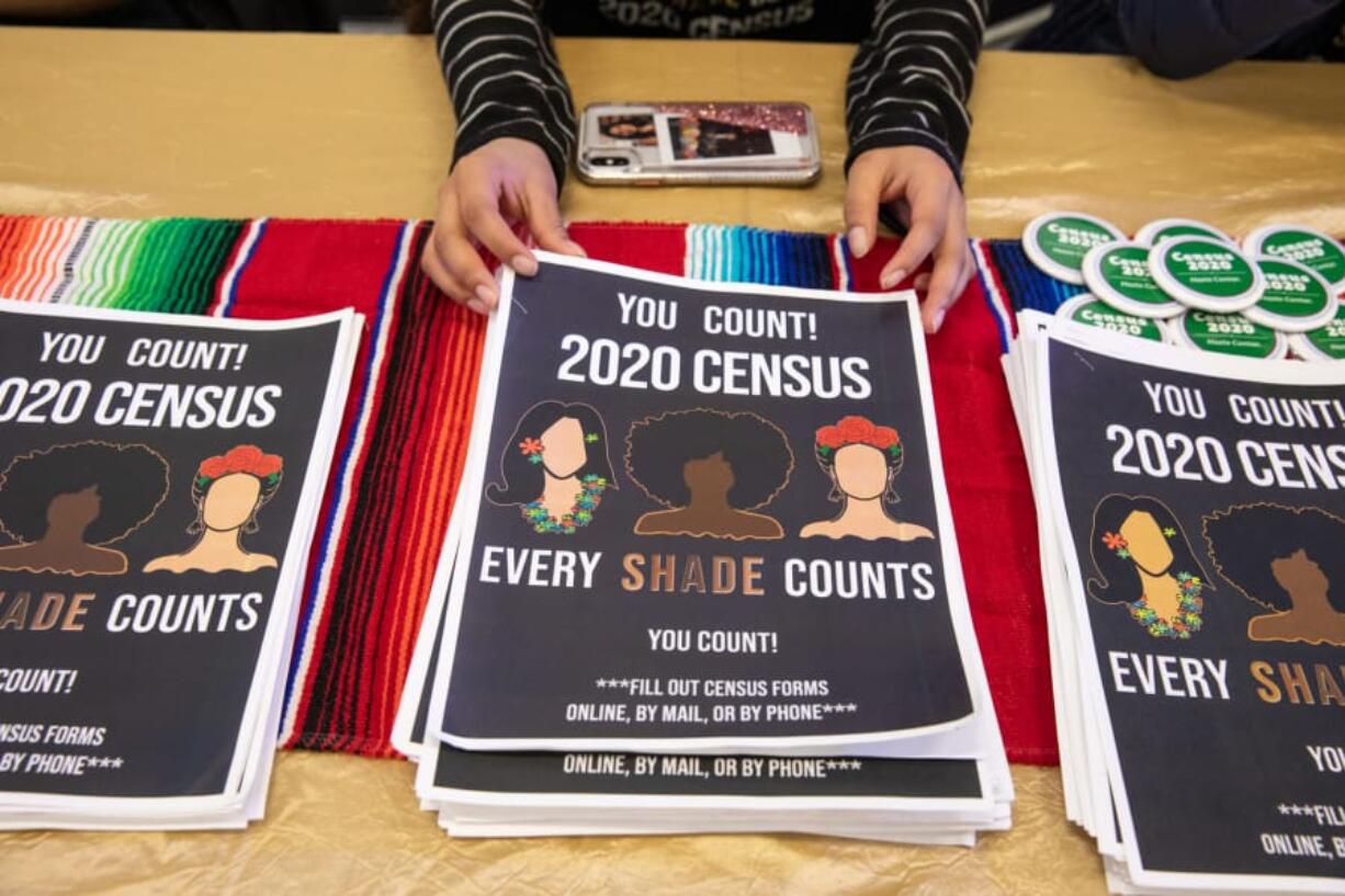 Alma Melchor, 17, a volunteer with the Southwest Washington Census Coalition, straightens a stack of information packets while working at a table at Expo Quinceanera NW on Feb. 29, 2020.