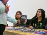 Alma Melchor, 17, right, and Carmen Huizar, center, both volunteers with the Southwest Washington Census Coalition, offer information about the importance of participating in the census to people arriving at Expo Quinceanera NW.
