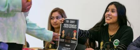 Alma Melchor, 17, right, and Carmen Huizar, center, both volunteers with the Southwest Washington Census Coalition, offer information about the importance of participating in the census to people arriving at Expo Quinceanera NW.