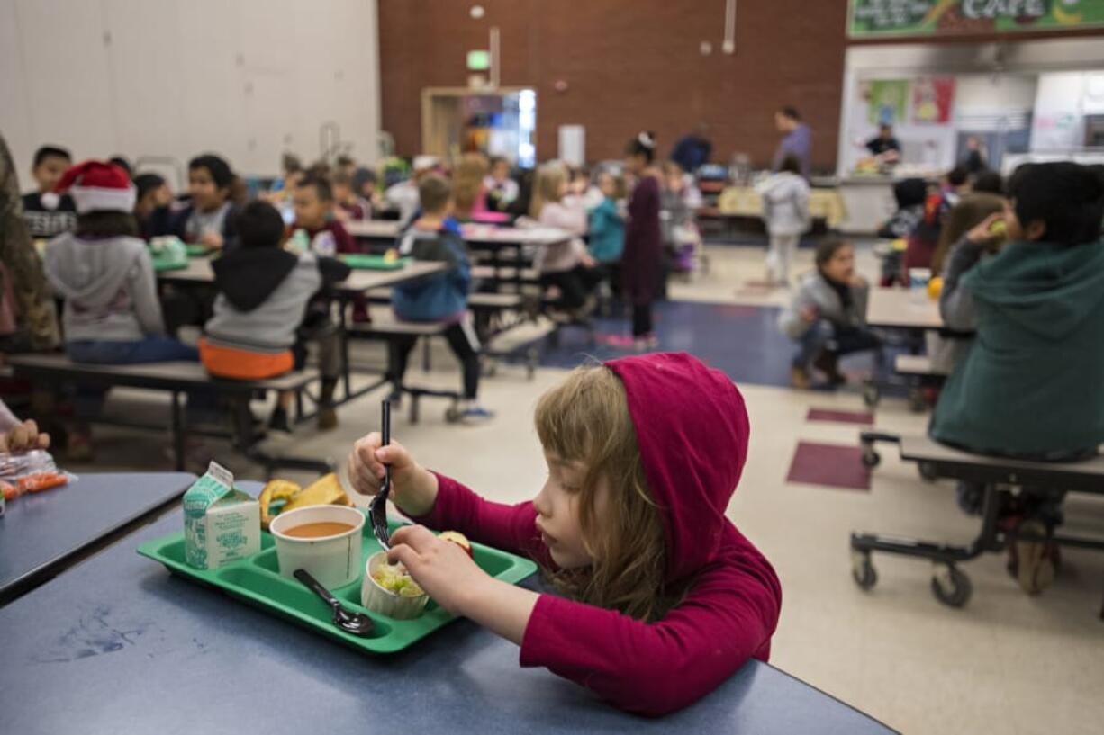 Nadine Shane, 6, a first-grader at Orchards Elementary School, dives into her lunch while dining with friends in the school&#039;s cafeteria in early 2020.