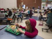 Nadine Shane, 6, a first-grader at Orchards Elementary School, dives into her lunch while dining with friends in the school&#039;s cafeteria in early 2020.