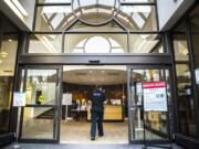 A medical worker walks past a sign informing visitors of health safety measures meant to prevent the spread of coronavirus at an entrance to PeaceHealth Southwest Medical Center in Vancouver.