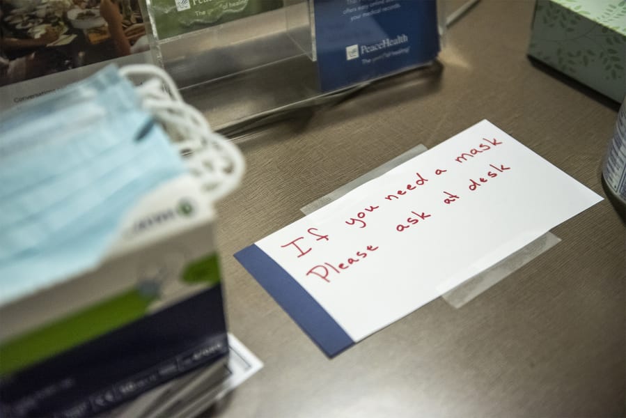 A sign directing visitors to the front desk if they are in need of a mask is seen at PeaceHealth Southwest Medical Center in Vancouver.