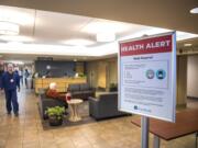 A medical worker walks past a sign informing visitors of health safety measures meant to prevent the spread of coronavirus at an entrance to PeaceHealth Southwest Medical on Monday afternoon, March, 2, 2020.