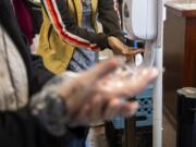 Clients disinfect their hands and put on plastic gloves before checking in at FISH of Vancouver on March 3, 2020. FISH is taking extra precautions to keep everything clean in response to the coronavirus.