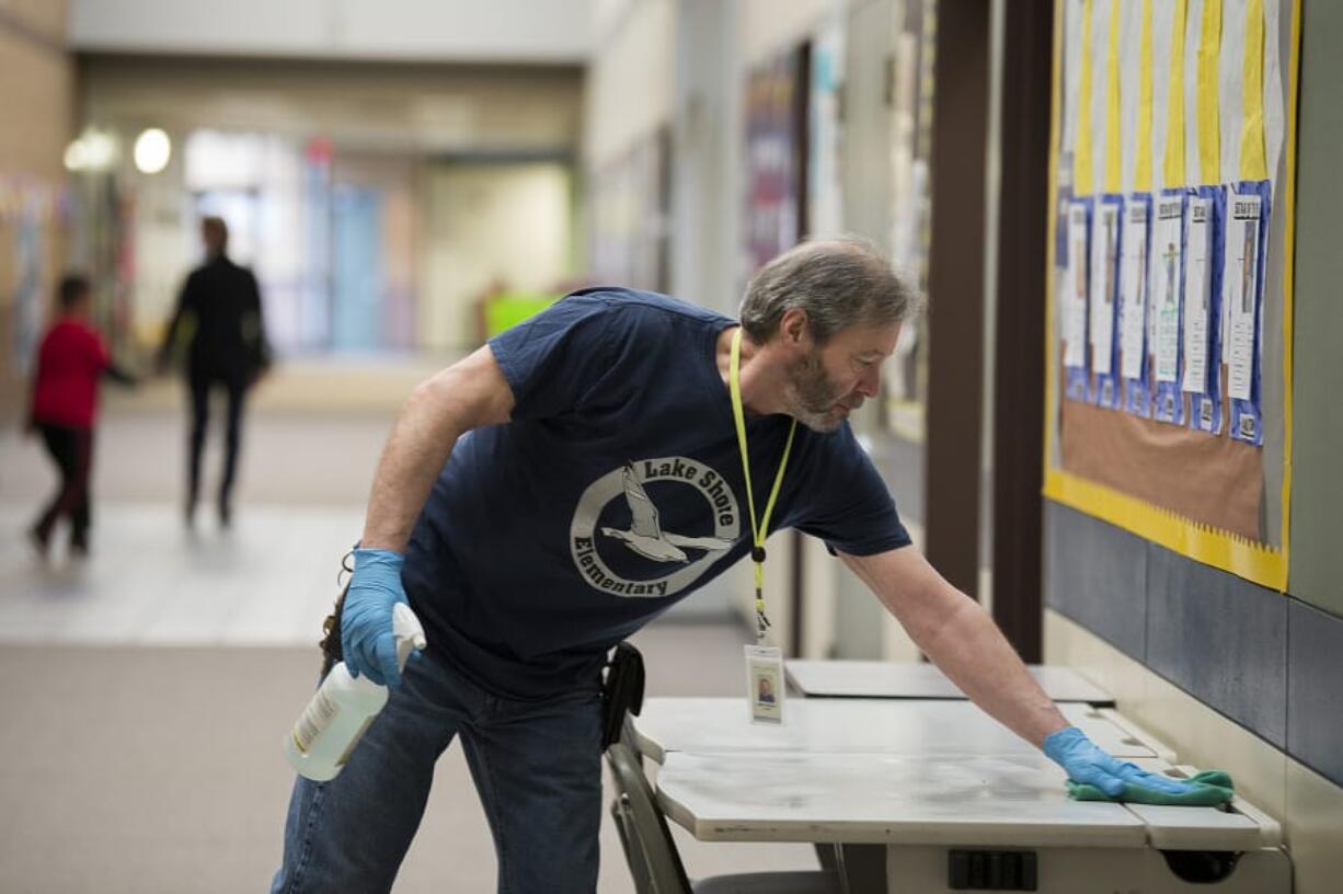 Mike Rodgers, building operator at Lake Shore Elementary School, wipes down tables in a hallway with disinfectant during preventative cleaning for COVID-19, as recommended by Clark County Public Health. Currently, the county has no confirmed cases of COVID-19, and officials said this was normal preventative cleaning.