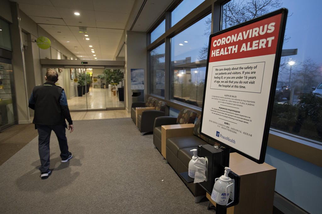 A man walks past a coronavirus health alert posted at one of the entrances to the Firstenburg Tower at PeaceHealth Southwest Medical Center on Monday morning.