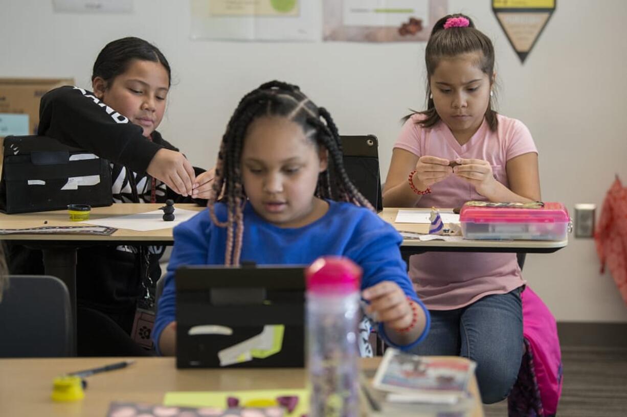 Fourth-graders Ahea Paongo, 10, from left, Amelia Blocker, 9, in blue, and Hailey Arriola, 10, in pink, use their creativity to bring clay to life while using an iPad at Peter S. Ogden Elementary School on Wednesday afternoon. Students had a hands-on experience with technology during a visit from the Vancouver school district&#039;s new Maker Mobile, a bus converted into a sort of roving craft room.