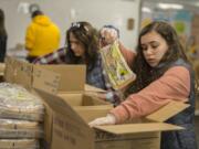Volunteers Kirsten Humber, left, and her daughter, Delaney, 16, help put together emergency food boxes at the Clark County Food Bank on Wednesday afternoon.