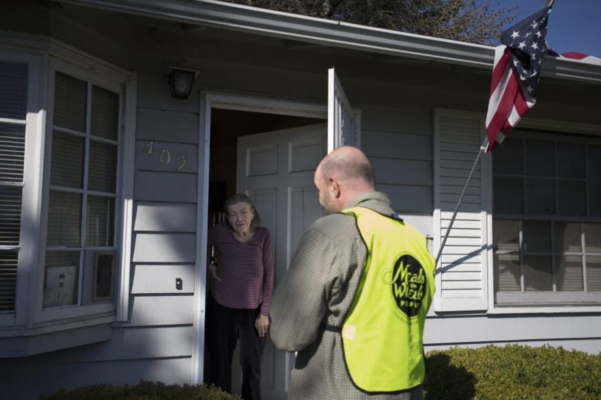 Fabiola Donnelly of Vancouver, left, chats with Luepke dining center manager Dean Scelza as he drops off a Meals on Wheels People food delivery on Monday morning. Scelza was careful not to shake hands or come too close to those on his delivery route to help prevent the spread of the novel coronavirus.