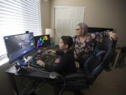 Alexander Monsalve, 13, plays a computer game while joined by his mom, Cecelia Jones, in his Vancouver bedroom Monday afternoon. The family, like most others in Clark County, are now confined to their home during the novel coronavirus outbreak.