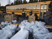 Jenny Cook, from left, Michael Vestal and Simone Farabee of Evergreen Public Schools help load up milk and meals near Burton Elementary School to be delivered to local students on Tuesday morning.