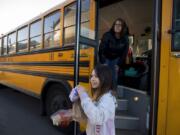 Kamryn Tanioka, 9, foreground, picks up her breakfast and lunch from school bus driver Tanisha Cardiel as she makes deliveries for students on her route in east Vancouver on March 17, 2020.