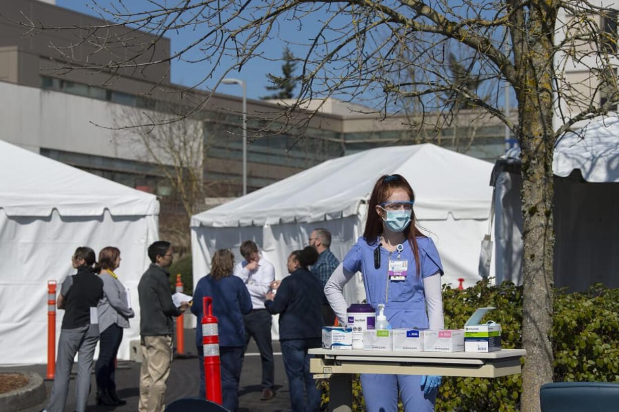 Certified nursing assistant Skye Jackson waits to greet incoming COVID-19 patients as staff in the emergency department meet to plan for a tent triage area at PeaceHealth Southwest Medical Center in Vancouver. The tents outside PeaceHealth are designed to separate possible COVID-19 cases from other emergency department patients.