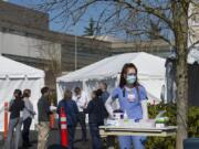 Certified nursing assistant Skye Jackson waits to greet incoming COVID-19 patients as staff in the emergency department meet to plan for a tent triage area at PeaceHealth Southwest Medical Center in Vancouver. The tents outside PeaceHealth are designed to separate possible COVID-19 cases from other emergency department patients.