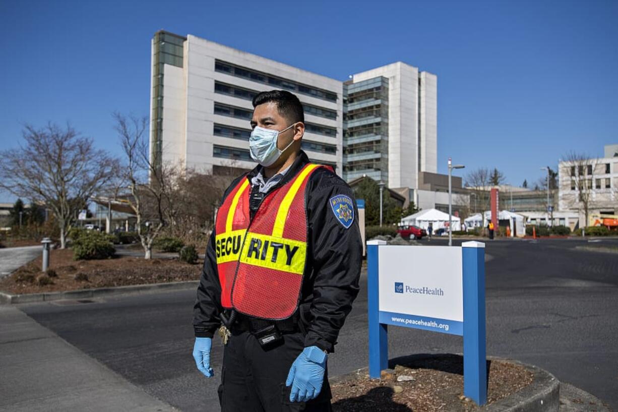 Frank Lopez, who works in security at PeaceHealth Southwest Medical Center in Vancouver, wears a mask and gloves as he waits to direct COVID-19 patients and other visitors Friday afternoon.