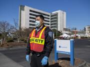 Frank Lopez, who works in security at PeaceHealth Southwest Medical Center in Vancouver, wears a mask and gloves as he waits to direct COVID-19 patients and other visitors Friday afternoon.