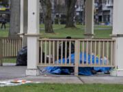 A person experiencing homelessness takes shelter underneath a gazebo at Esther Short Park on Wednesday morning.