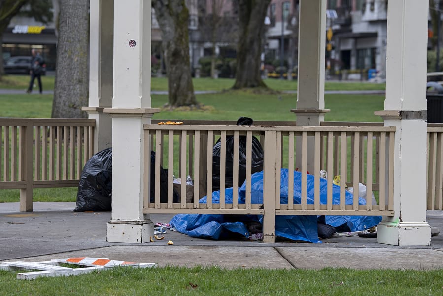 A person experiencing homelessness takes shelter underneath a gazebo at Esther Short Park on Wednesday morning.