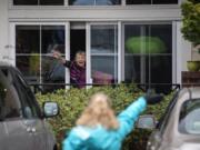 Touchmark resident Gladys Meier waves at staff members as an outdoor parade moves by her window through the parking lot at the senior living community in Vancouver on Thursday.