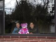 Lucy Hackett, 9, left, and her brother Henry, 10, left notes on neighbors&#039; front porches to encourage them to put stuffed bears in their windows for people to spot as they walk by. At top, Lucy holds out one of the notes she and her brother wrote to ask neighbors to participate in a bear-hunt game in which they put teddy bears in their front windows for kids to spot.