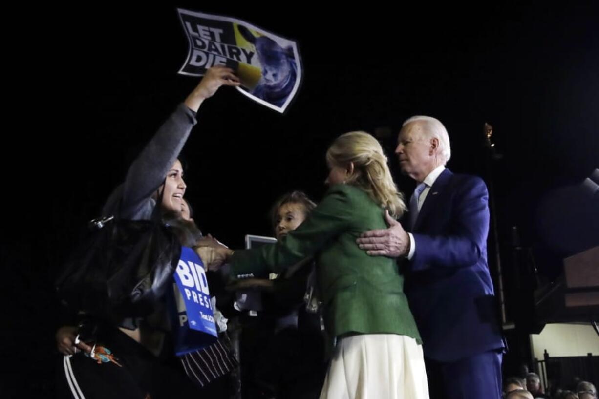 A protester at left, is held back by Jill Biden, center, and her husband Democratic presidential candidate former Vice President Joe Biden, right, during a primary election night rally Tuesday, March 3, 2020, in Los Angeles.