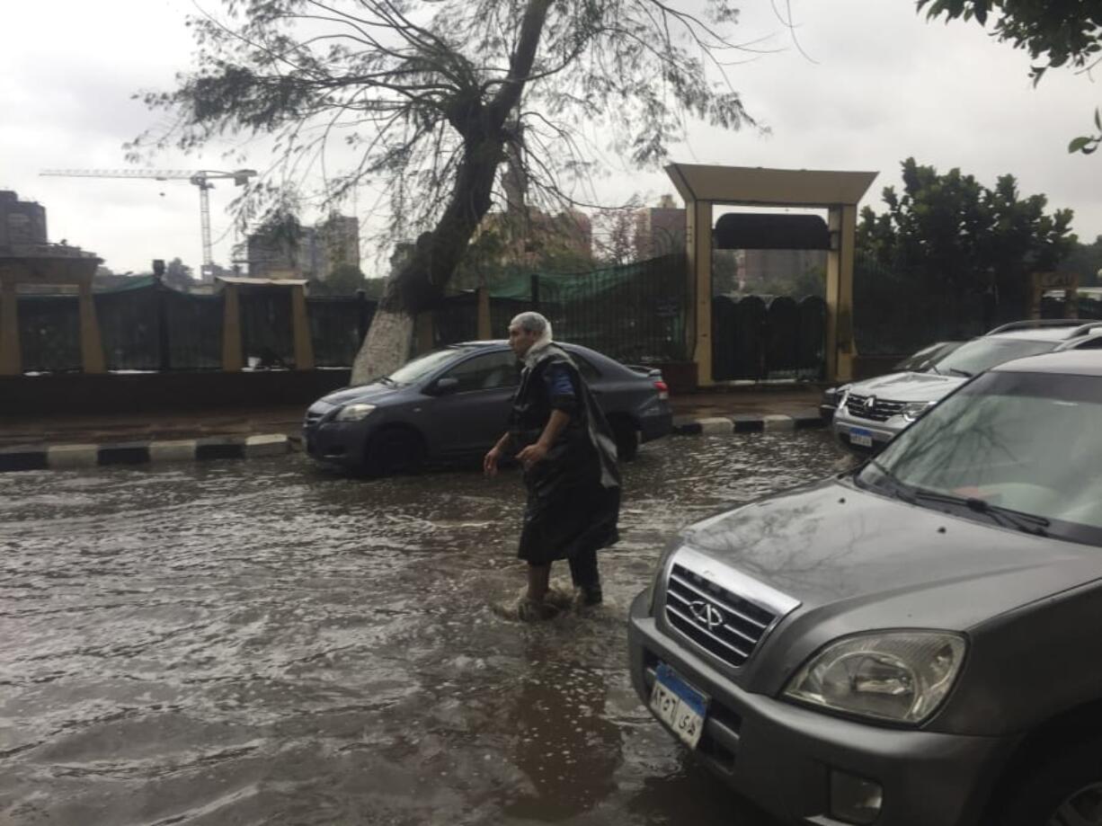 A man wears makeshift rain gear as he navigates a flooded road after heavy rains in the Zamalek district of Cairo, Egypt, Thursday, March 12, 2020. Thunderstorms packing heavy rains and lightning caused widespread flooding in Egypt on Thursday, killing several people and causing authorities to shut down schools and an airport, officials said.