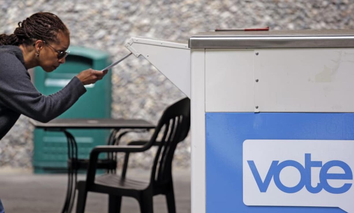 FILE - In this Aug. 2, 2018 file photo, Eudora Carter inserts her ballot into a drop-off voting box in Seattle. Washington is among half a dozen states in the Democratic presidential primary spotlight on Tuesday, March 10, 2020.