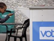 FILE - In this Aug. 2, 2018 file photo, Eudora Carter inserts her ballot into a drop-off voting box in Seattle. Washington is among half a dozen states in the Democratic presidential primary spotlight on Tuesday, March 10, 2020.