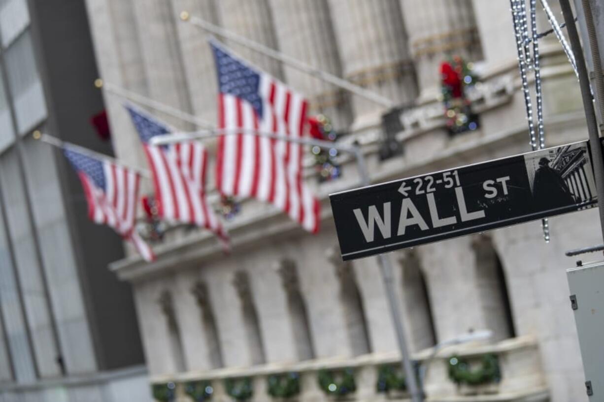 FILE - In this Jan. 3, 2020 file photo, the Wall St. street sign is framed by American flags flying outside the New York Stock Exchange in New York.   Stocks dropped 10% in early trading Monday, March 16,  on Wall Street as huge swaths of the economy come closer to shutting down, from airlines to restaurants.