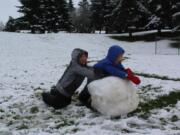 Cady Mae Yurkewycz, 8, left, and her 5-year-old sister Mary Lou take advantage of the March 14 morning snowfall at Franklin Park in Vancouver.