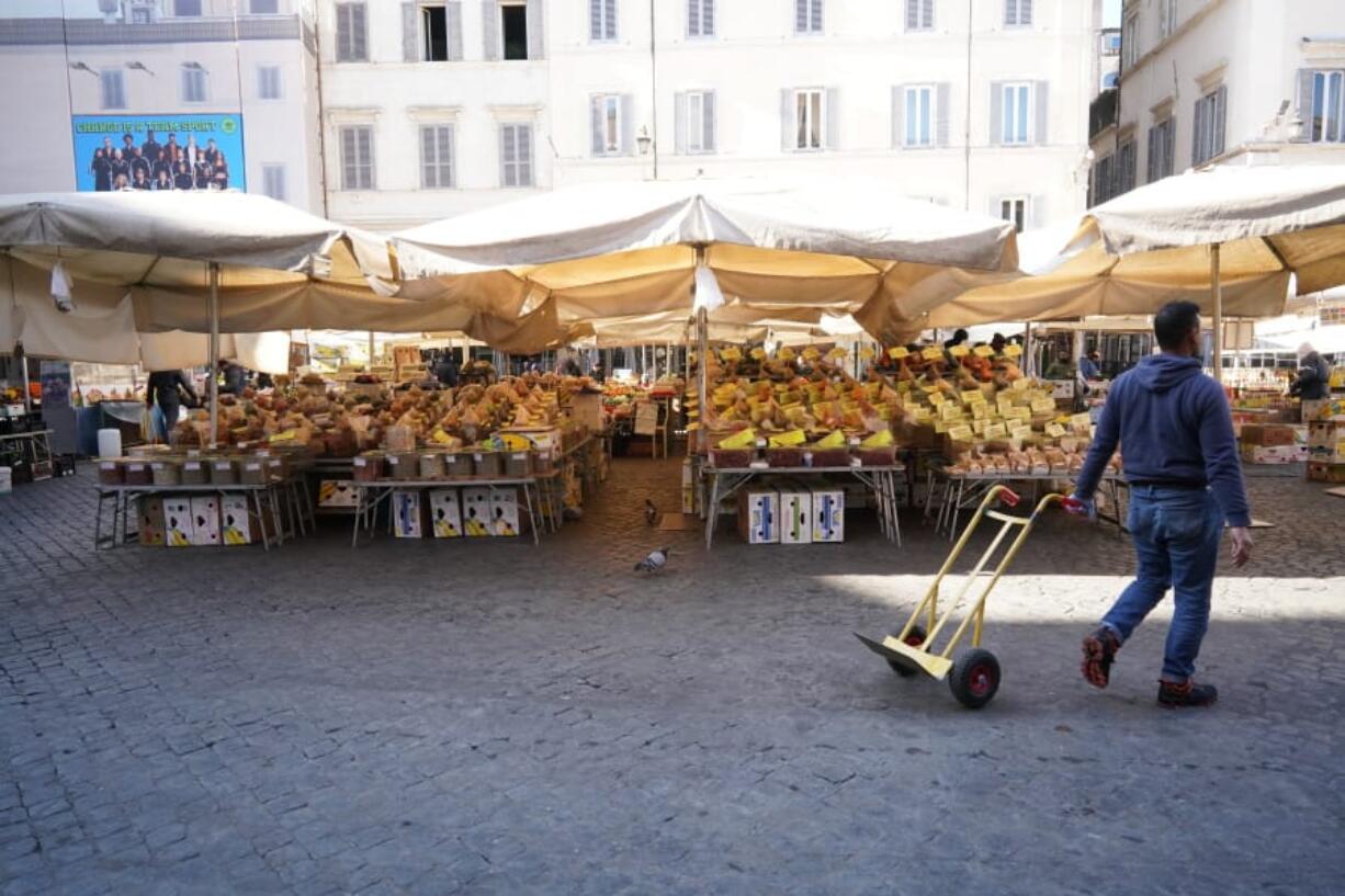 A man pulls a trolley at an emtpy Campo dei Fiori open-air market, in Rome, Tuesday, March 10, 2020. The Italian government is assuring its citizens that supermarkets will remain open and stocked after panic buying erupted after broad anti-virus measures were announced nationwide, sparking overnight runs on 24-hour markets.