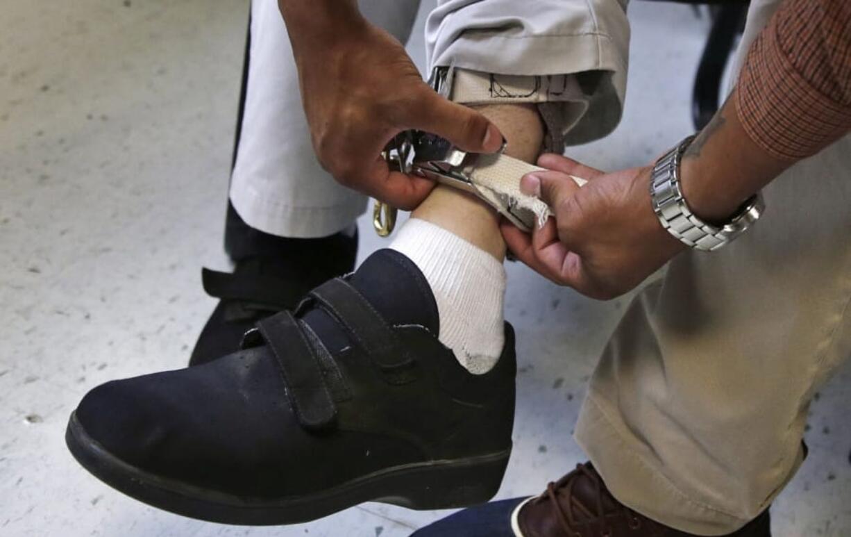 A therapist checks the ankle strap of an electrical shocking device on a student during an exercise program at the Judge Rotenberg Educational Center in Canton, Mass. The student, who was born with a developmental disorder, wears the device so administrators can control violent episodes.