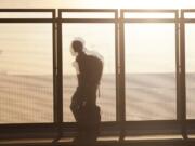 FILE - In this June 26, 2019, file photo a traveller is silhouetted by the setting sun while running past a wind partition in the bus lanes at Denver International Airport in Denver. Whether visiting an exotic destination wedding or just flying back to Cincinnati for your awkward cousin&#039;s nuptials, wedding travel can get expensive in a hurry.