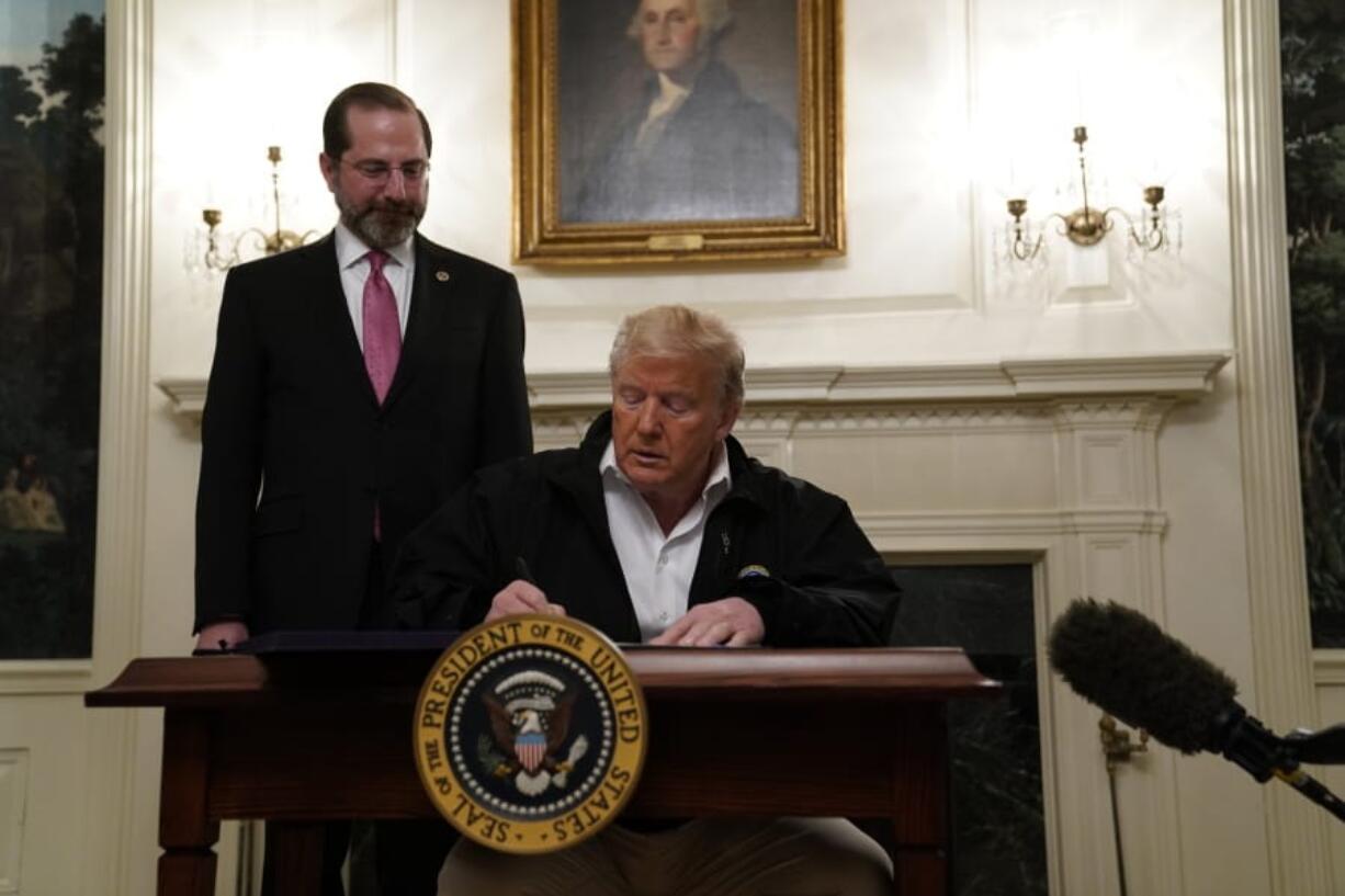 President Donald Trump signs an $8.3 billion bill to fight the coronavirus outbreak in the U.S., Friday, March 6, 2020 at the White House in Washington, as Department of Health and Human Services Secretary Alex Azar, looks on.  The legislation provides federal public health agencies with money for vaccines, tests and potential treatments and helps state and local governments prepare and respond to the threat. The rapid spread of the virus has rocked financial markets, interrupted travel and threatens to affect everyday life in the United States.