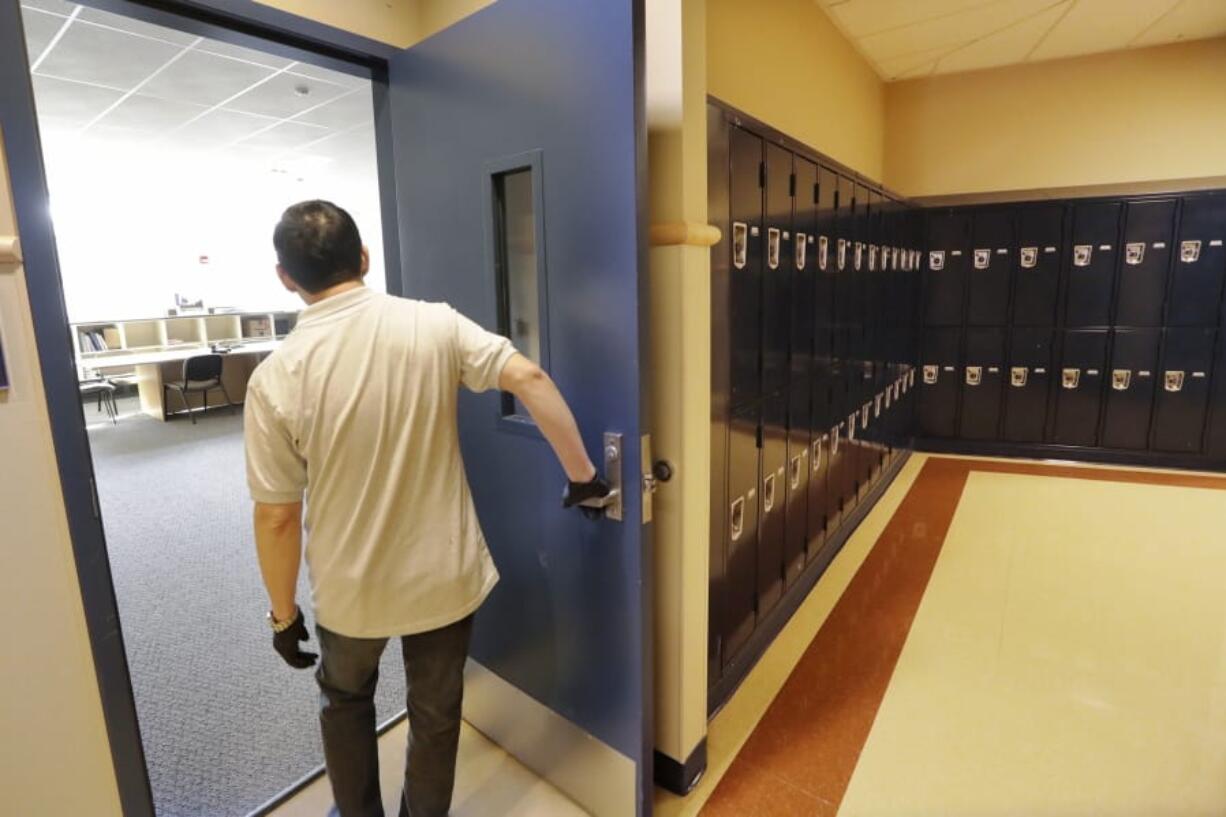 A school janitor opens the door to a staff room Feb. 27 inside Bothell High School, which was closed for the day, in Bothell, after a staffer&#039;s family member was placed in quarantine for showing symptoms of possibly contracting the new coronavirus.