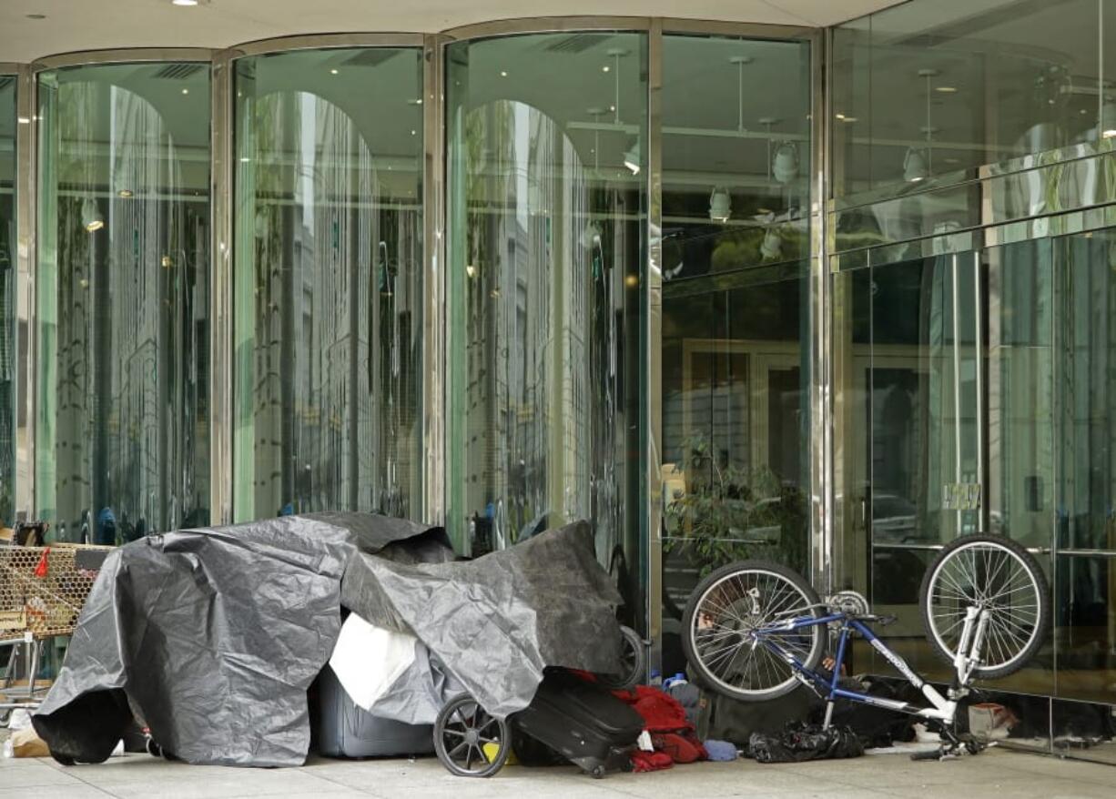 Homeless people camp out in from of the San Francisco Ballet Wednesday, March 18, 2020, in San Francisco. Officials in seven San Francisco Bay Area counties have issued a shelter-in-place mandate affecting about 7 million people, including the city of San Francisco itself. The order says residents must stay inside and venture out only for necessities for three weeks starting Tuesday.